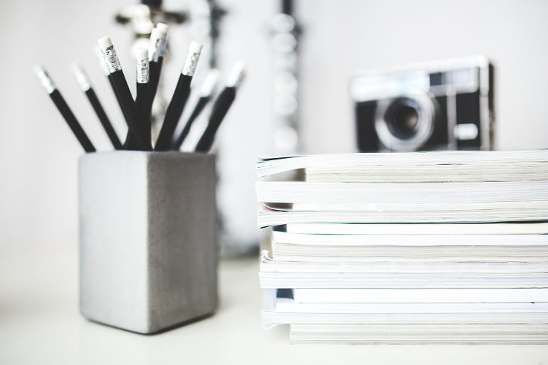 Desktop with pencils, notebooks, and a camera on display.